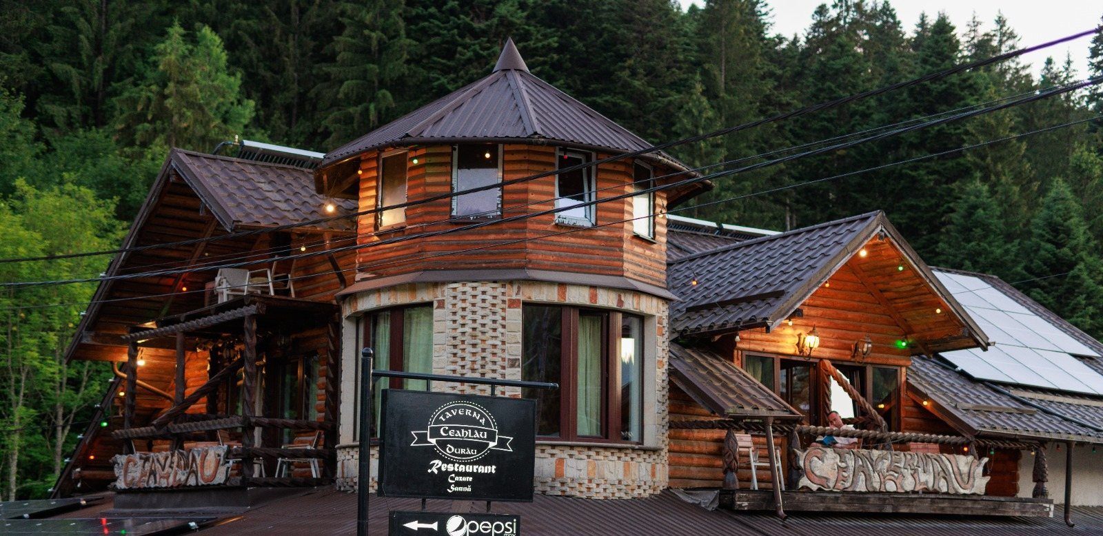Fațada din lemn a Tavernei Ceahlău, luminată în amurg